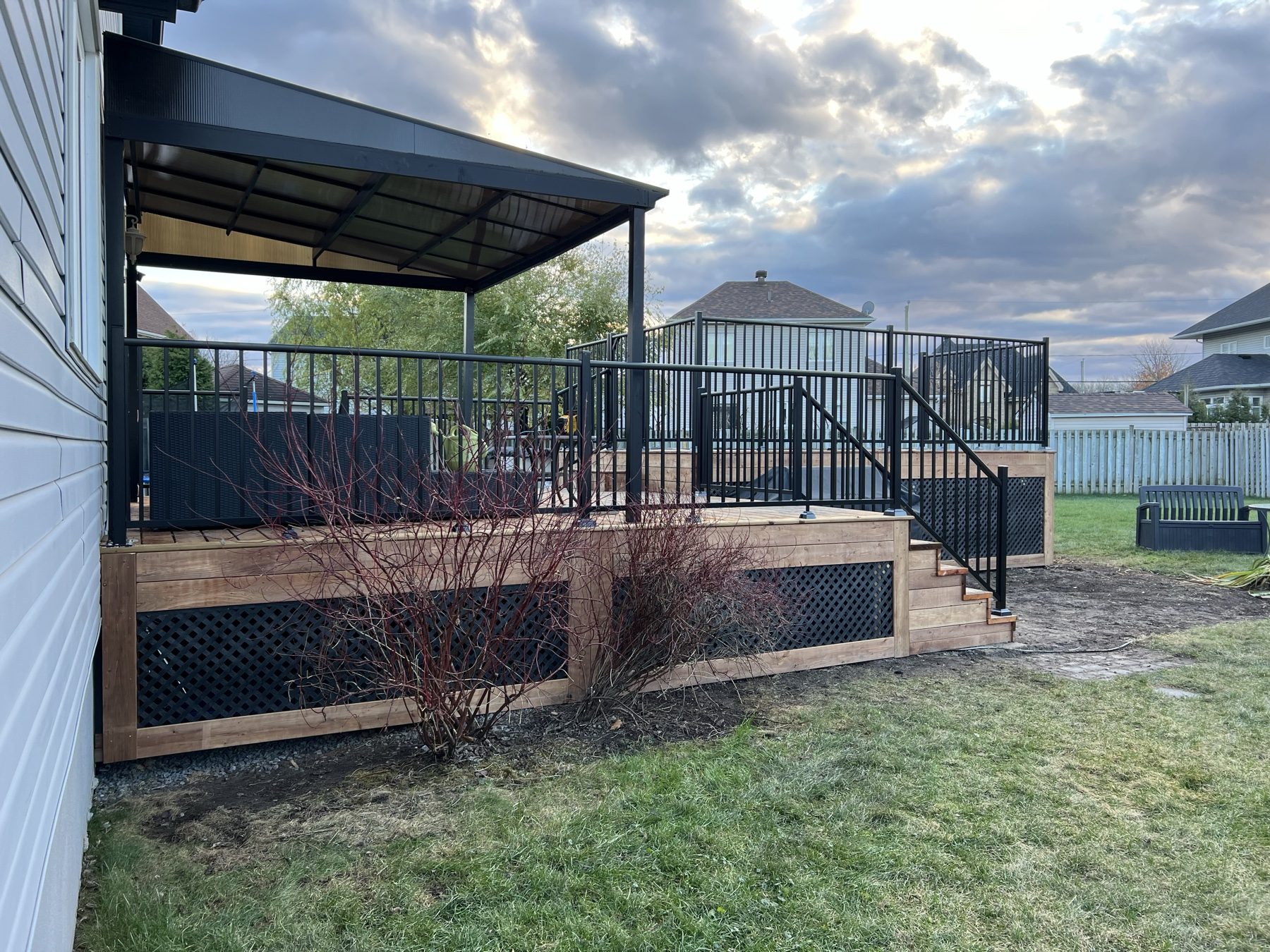 Raised deck with black aluminum railings, lattice skirting and a gazebo roof