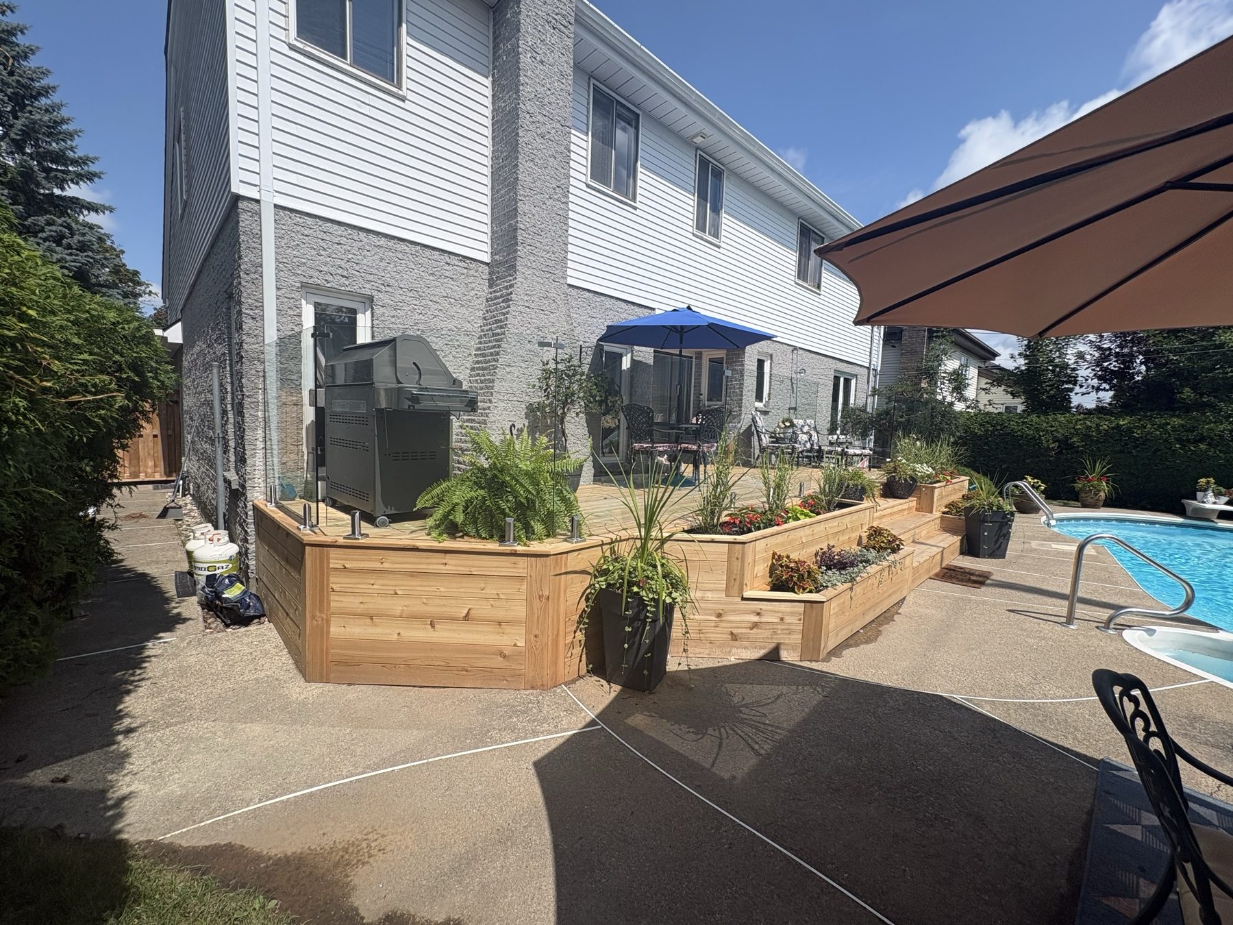 Wide poolside deck with built in cedar planters and outdoor seating