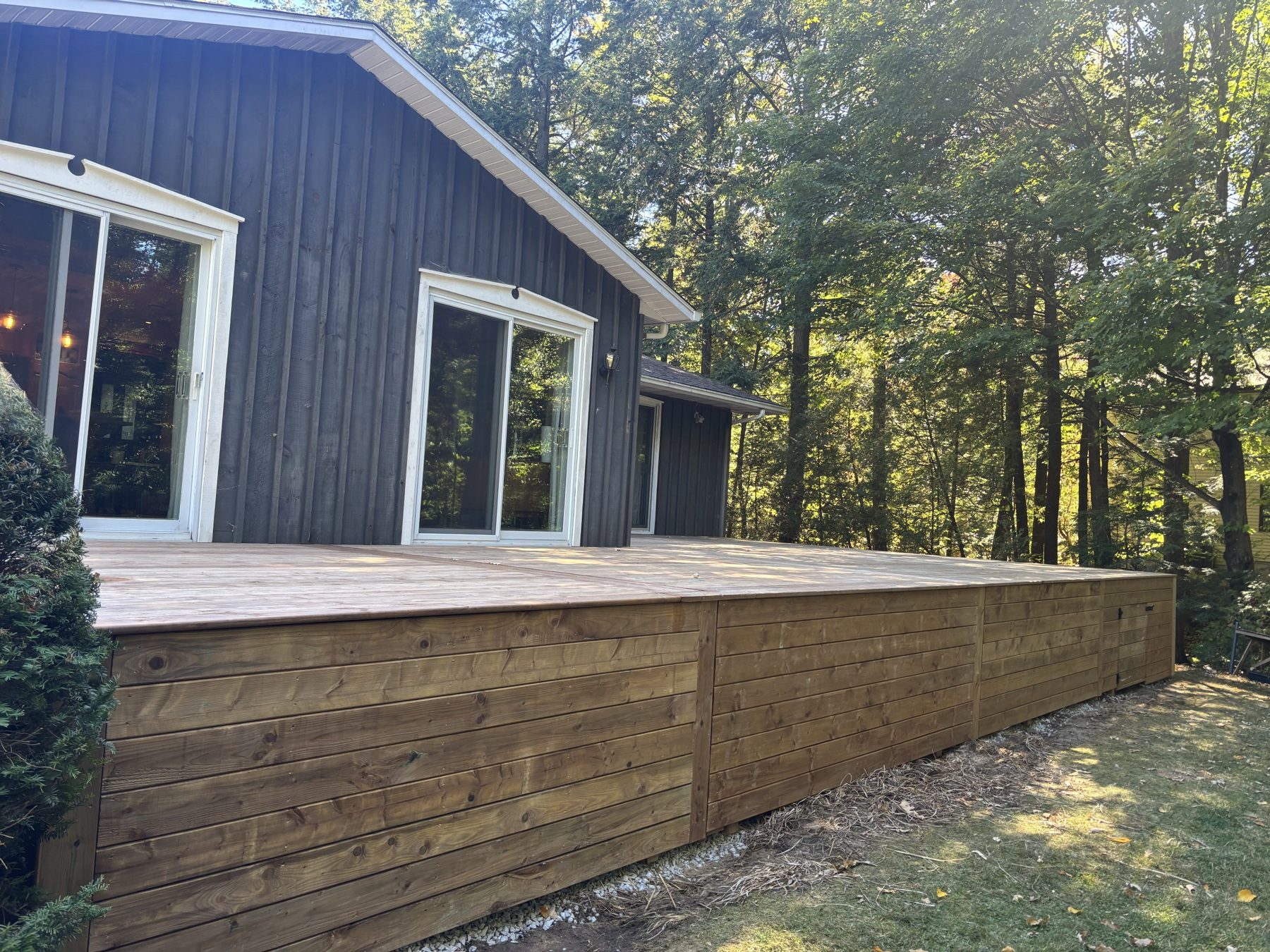 Long raised wood deck with horizontal skirting on a wooded lot
