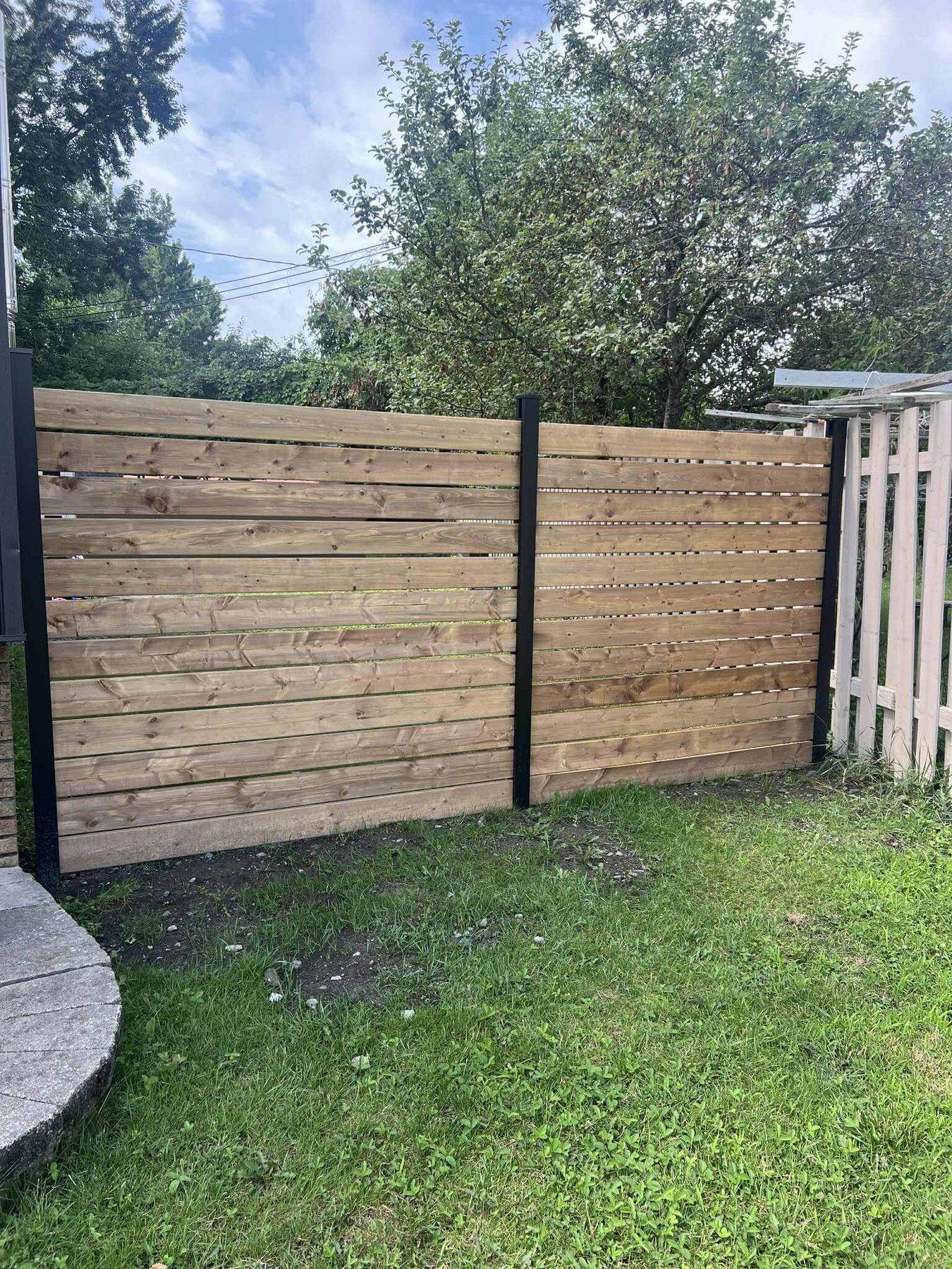 Horizontal cedar privacy fence panels between dark posts